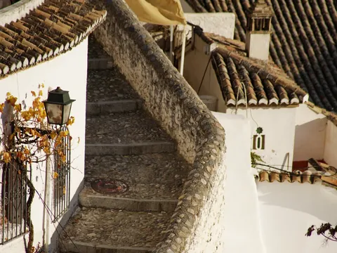 Callejuela empedrada con escaleras y casas blancas típicas del Albaicín, Granada