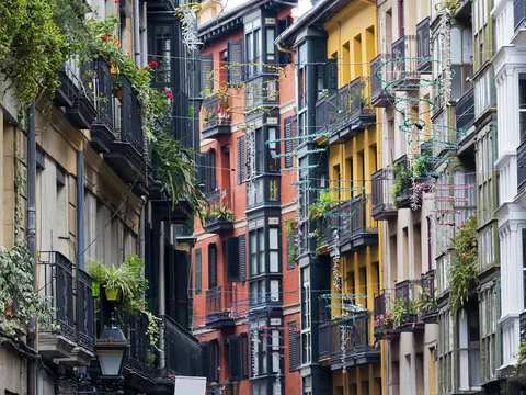Fachadas coloridas y balcones con plantas en una calle estrecha del Casco Viejo de Bilbao.