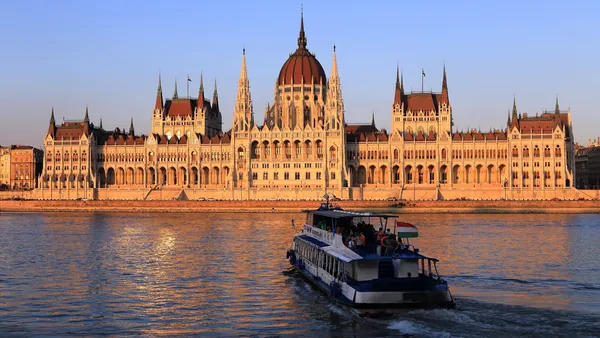 Crucero navegando por el Danubio con el Parlamento de Budapest al atardecer.