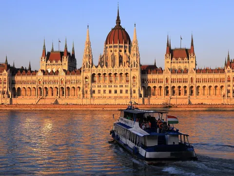 Crucero navegando por el Danubio con el Parlamento de Budapest al atardecer.