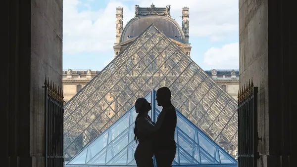 Pareja en silueta frente a la Pirámide del Louvre en París.