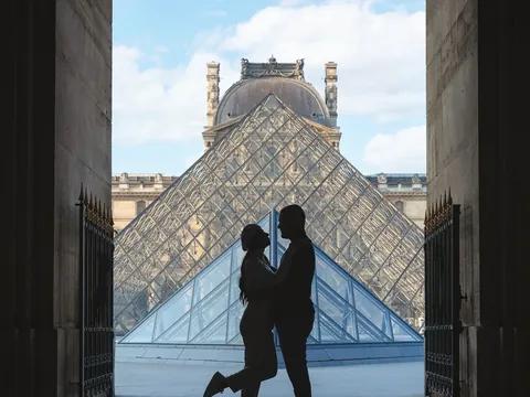 Pareja en silueta frente a la Pirámide del Louvre en París.
