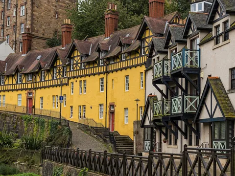 Vista de la arquitectura típica de Dean Village, con sus casas de piedra de estilo escocés y tejados a dos aguas, rodeadas de naturaleza.
