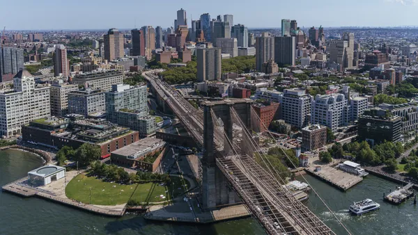 Vista aérea del puente de Brooklyn y los rascacielos de la ciudad de Nueva York, con un parque junto al agua.