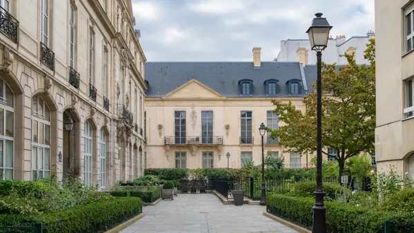 ardín francés frente al Hôtel de Sully en el barrio del Marais, París, con setos geométricos y fachada renacentista.