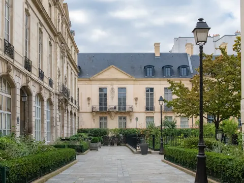 ardín francés frente al Hôtel de Sully en el barrio del Marais, París, con setos geométricos y fachada renacentista.
