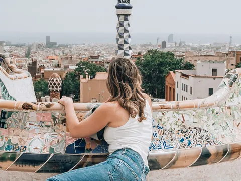 Persona admirando la vista de Barcelona desde el colorido banco del Parque Güell