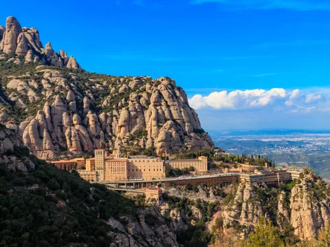 Monasterio de Montserrat rodeado de montañas rocosas bajo cielo azul.