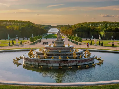 Fuentes en el exterior del Palacio de Versalles, rodeadas de jardines bien cuidados y arquitectura clásica.