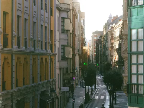 Calle comercial del centro de Gijón con arquitectura clásica y galerías verdes.