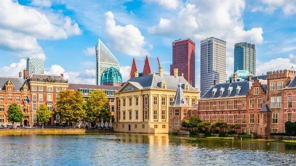 Vista panorámica del Hofvijver en La Haya, Países Bajos, con edificios históricos rodeando el estanque en primer plano y modernos rascacielos de cristal y metal al fondo