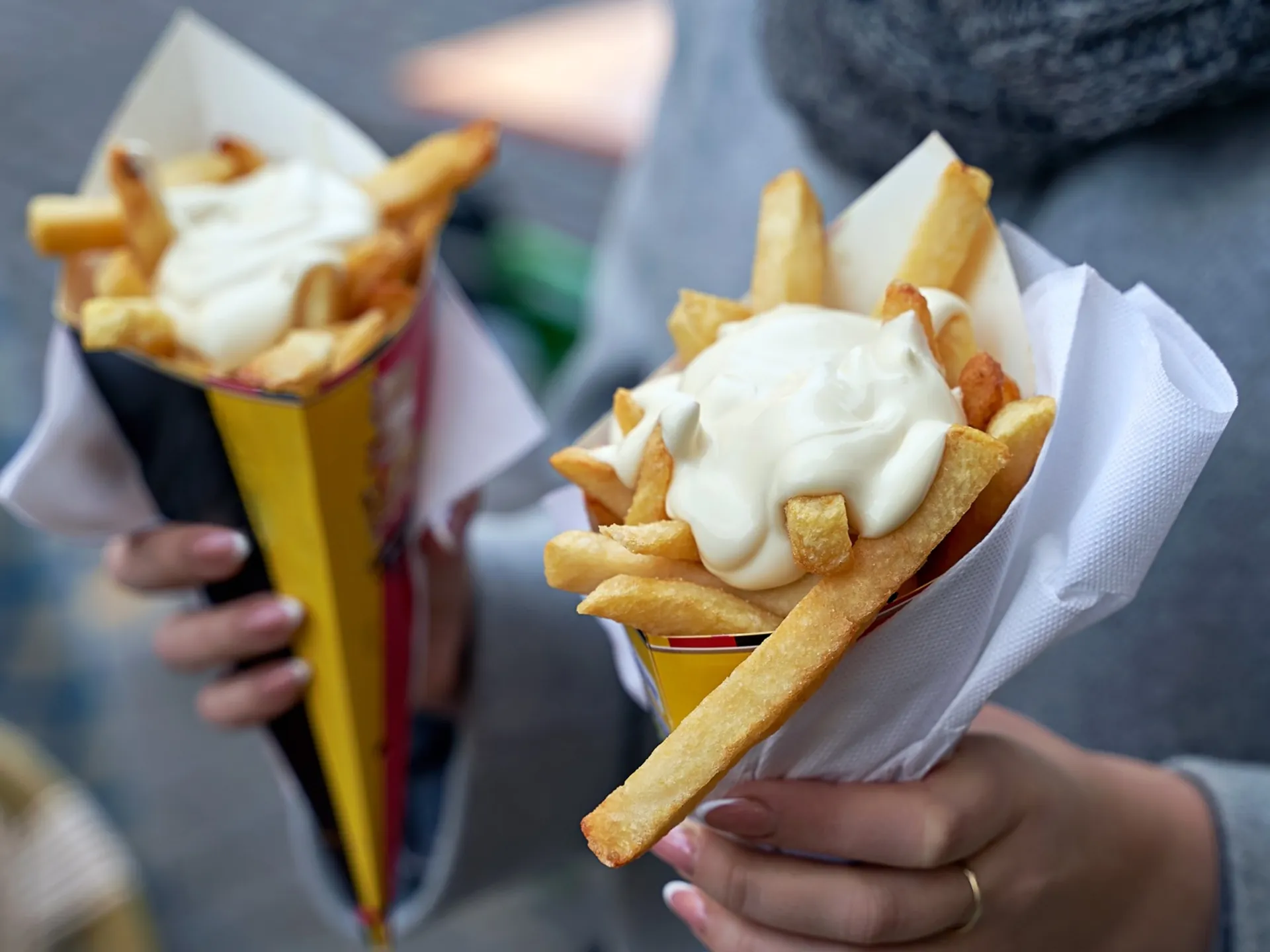 Dos cucuruchos de patatas fritas con mayonesa.