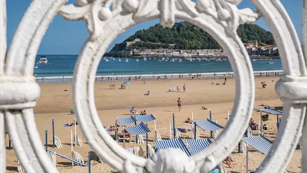 Vista de la playa de La Concha en San Sebastián enmarcada por la barandilla blanca.