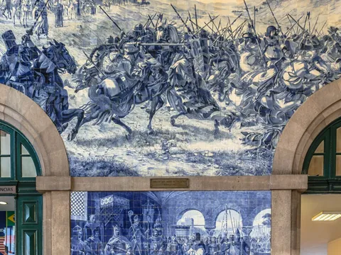 Paneles de azulejos azules en São Bento con escenas históricas de batallas medievales.