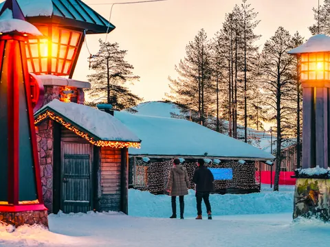 Pareja paseando por el pueblo de Papá Noel al atardecer.