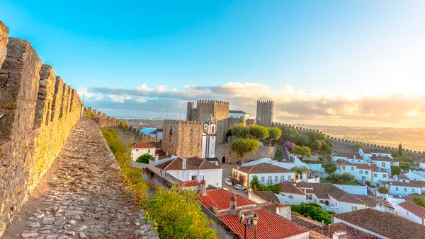 Murallas y castillo de Óbidos al atardecer con vistas al pueblo de casas blancas.