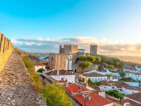 Murallas y castillo de Óbidos al atardecer con vistas al pueblo de casas blancas.