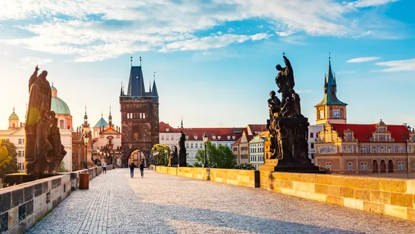 Puente de Carlos al amanecer con esculturas y la Torre de la Ciudad Vieja en Praga