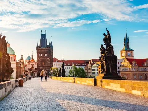Puente de Carlos al amanecer con esculturas y la Torre de la Ciudad Vieja en Praga