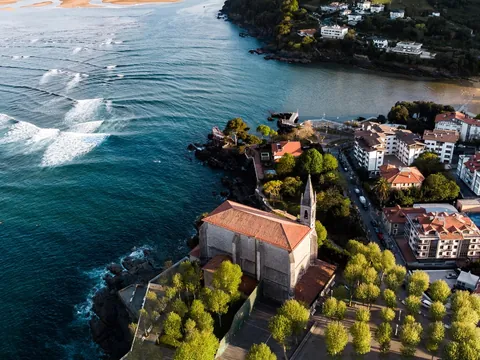 Vista aérea de la iglesia de Santa María y olas en la ría de Mundaka, Vizcaya