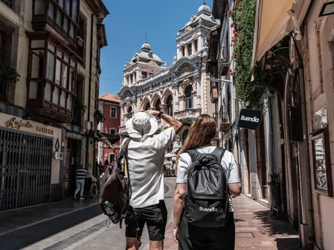 Turistas paseando por una calle del centro histórico de Llanes, admirando la arquitectura típica asturiana bajo el sol.