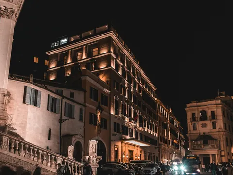 Edificios clásicos y escalinatas iluminadas en una calle de Roma por la noche.