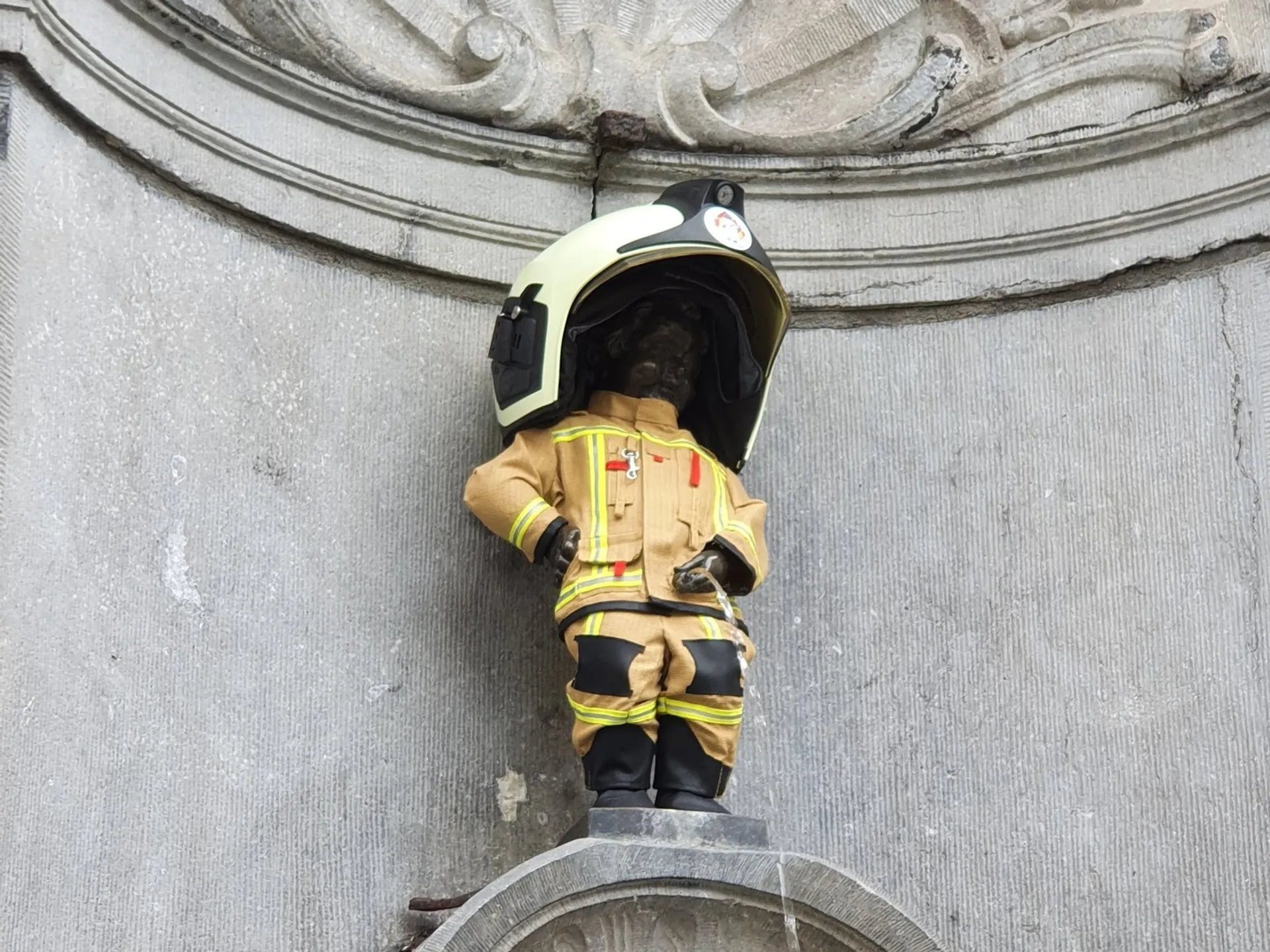 Estatua del Manneken Pis vestido de bombero con casco y uniforme en Bruselas