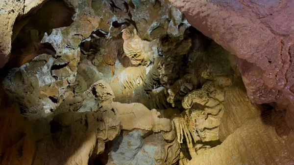 Interior de una cueva con formaciones geológicas como estalactitas, estalagmitas y coladas.