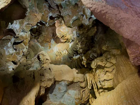 Interior de una cueva con formaciones geológicas como estalactitas, estalagmitas y coladas.