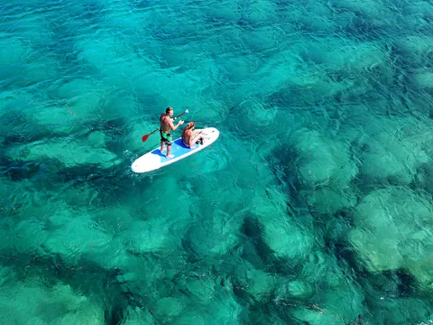 Pareja practicando paddle surf en las aguas de una cala de Mallorca