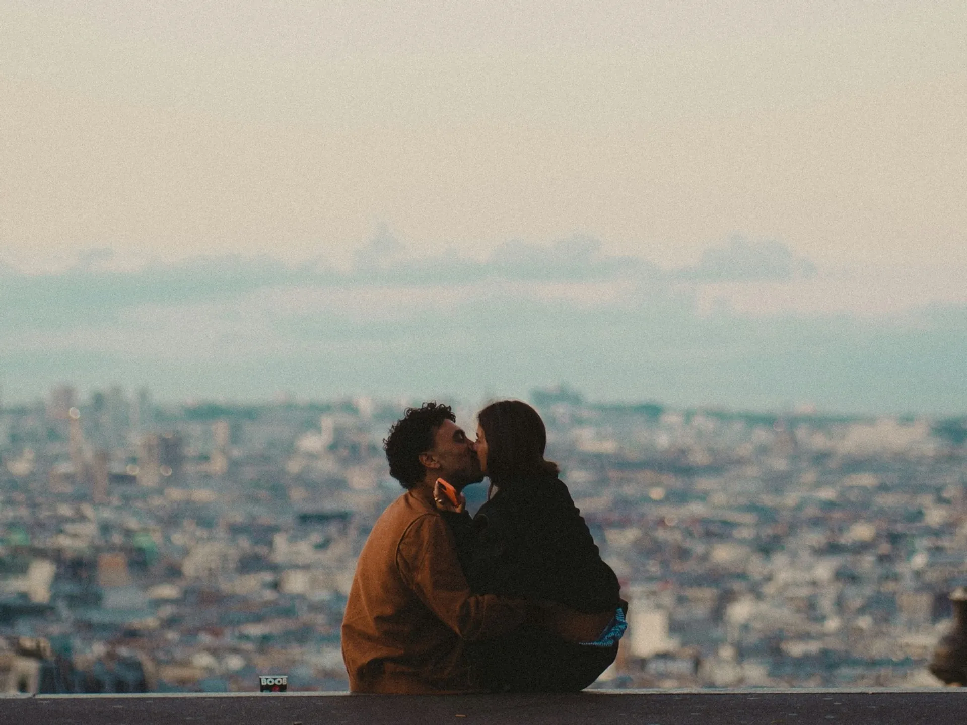 Pareja besándose al atardecer en Montmartre con vistas panorámicas de París.