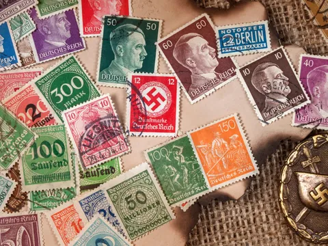 Colección de sellos postales del Tercer Reich y medalla con esvástica nazi.