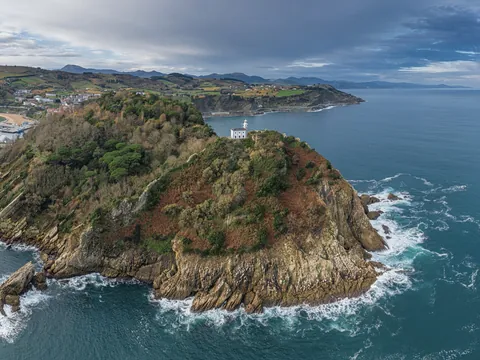Isla con faro en la costa de Getaria rodeada por acantilados y mar.
