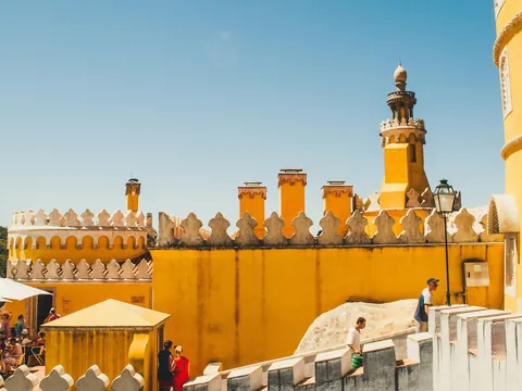 Terraza amarilla del Palacio da Pena con turistas bajo el sol en Sintra.