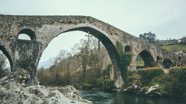 Puente Romano de Cangas de Onís en Asturias, con la emblemática Cruz de la Victoria colgando sobre el río Sella.