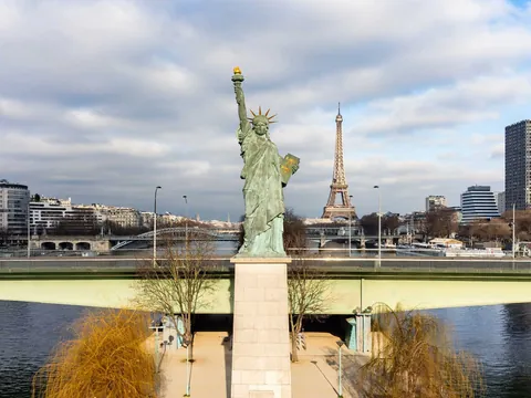Estatua de la Libertad en París con la Torre Eiffel al fondo junto al río Sena.