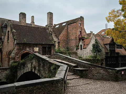 Puente de piedra sobre un canal con casas medievales de ladrillo en Brujas, Bélgica.