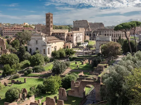 Vista del Foro Romano en Roma con ruinas, vegetación y el Coliseo al fondo