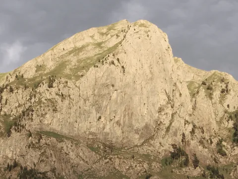 Pico de la Peña Oroel, un macizo rocoso y escarpado en los Pirineos cerca de Jaca, bajo un cielo nublado y oscuro.
