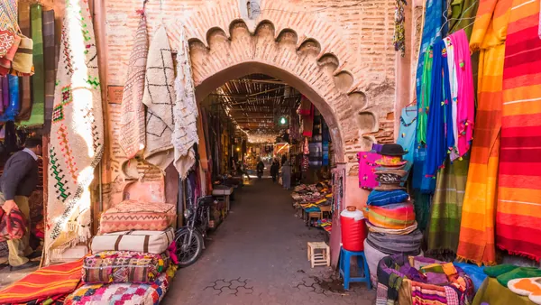 Calle comercial de la Medina de Marrakech con alfombras y puestos tradicionales