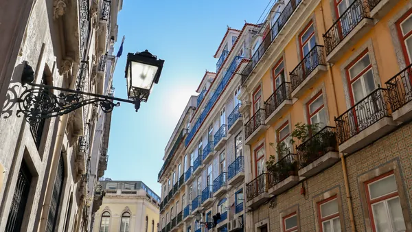 Calle del centro de Lisboa con fachadas de azulejos y balcones de hierro forjado.
