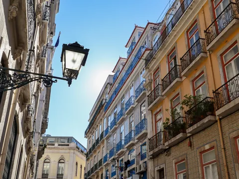 Calle del centro de Lisboa con fachadas de azulejos y balcones de hierro forjado.