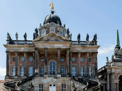 Fachada y escalinata principal del Nuevo Palacio (Neues Palais) en Potsdam, con estatuas y cúpula barroca.