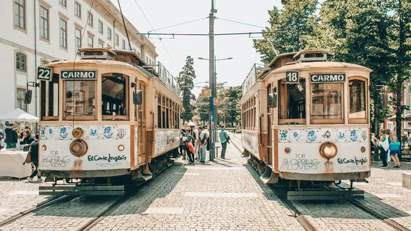 Dos tranvías históricos de Oporto en la línea de Carmo con gente a su alrededor.