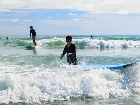 Niño en clase de surf entre olas en la playa de Mundaka, Vizcaya