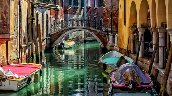 Vista de uno de los canales de Venecia, con un pequeño puente y góndolas