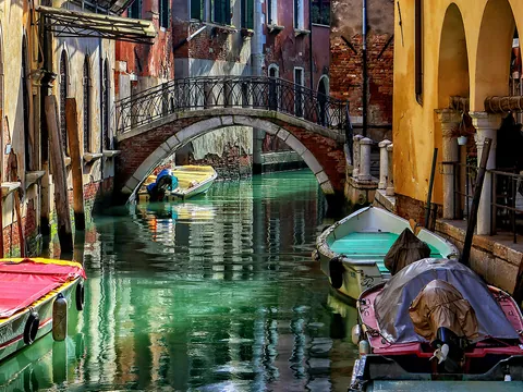 Vista de uno de los canales de Venecia, con un pequeño puente y góndolas