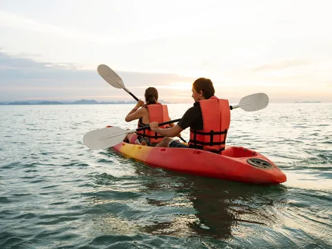 Pareja remando en kayak doble por la costa de Menorca