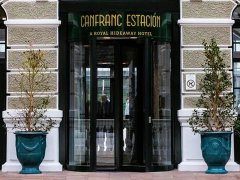 Entrada principal con puerta giratoria del Canfranc Estación, A Royal Hideaway Hotel, con maceteros flanqueando la puerta.