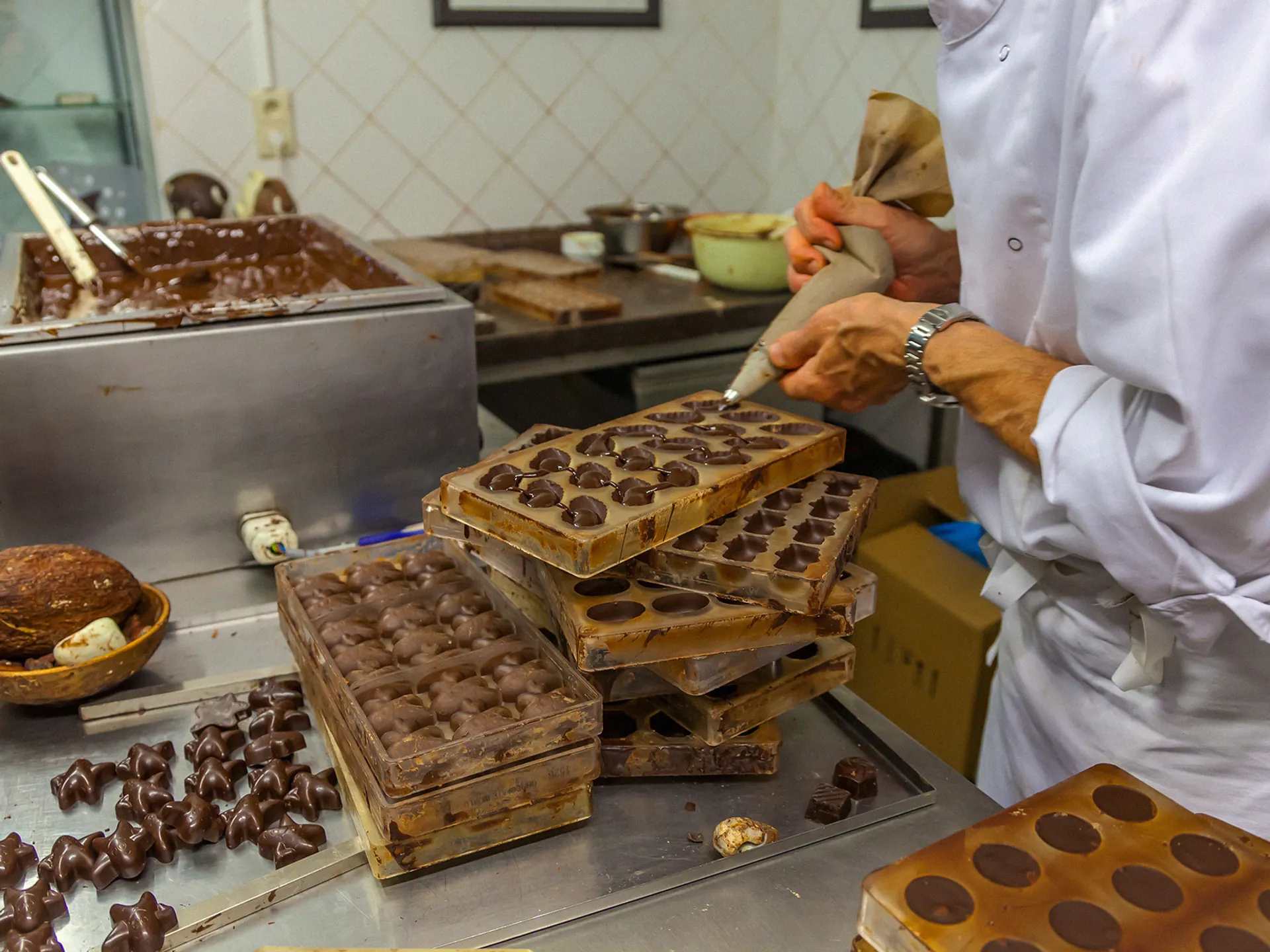 Maestro chocolatero rellenando moldes de bombones en un taller de Bruselas